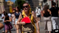 Seorang perempuan tampak mengipasi dirinya ketika berjalan di Madrid, Spanyol, di tengah cuaca panas pada 10 Juli 2023. (Foto: AP/Manu Fernandez)