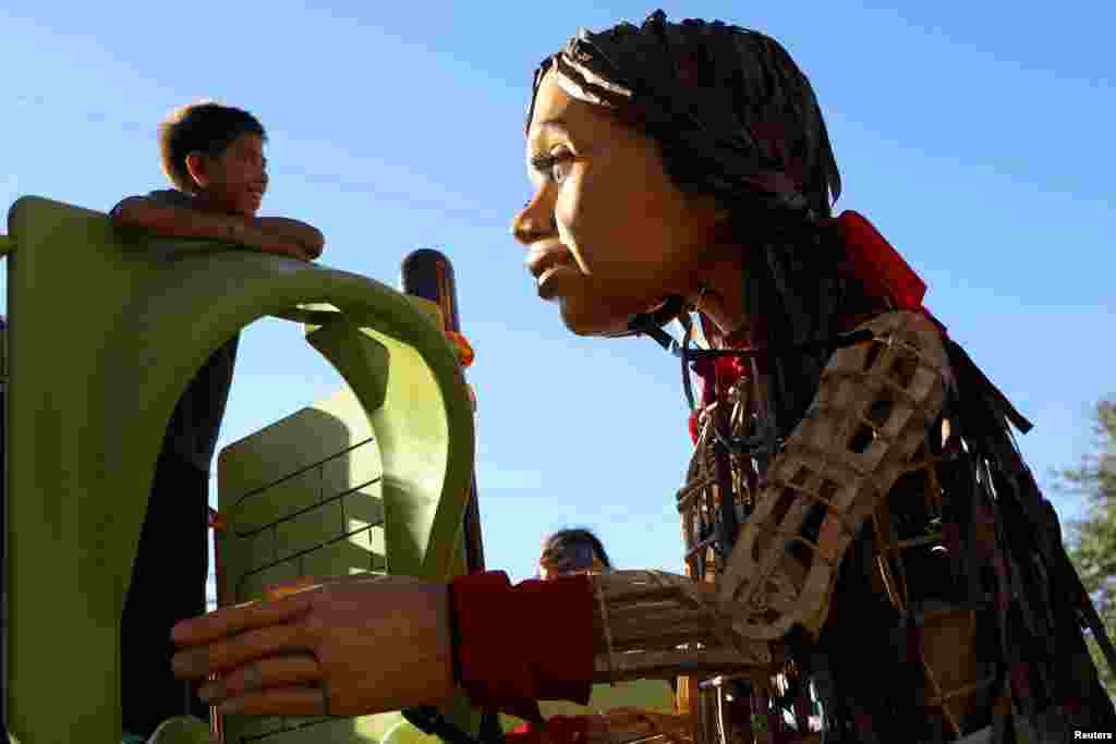 A pequena Amal, uma marioneta de 12 pés de altura que representa uma refugiada síria de 10 anos, brinca com Fabian, um rapaz migrante venezuelano, durante a sua viagem ao longo da fronteira EUA-México em El Paso, Texas, 25 de outubro de 2023.