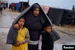 Pengungsi Palestina berjalan setelah hujan lebat di kamp di Rafah, selatan Jalur Gaza, 13 Desember 2023. (Foto: REUTERS/Mohammed Salem)