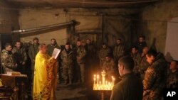 Pendeta Ivan dari Gereja Ortodoks Ukraina membacakan doa untuk prajurit Ukraina dari brigade mekanik ke-72 selama liturgi suci sebelum Natal mendatang di garis depan dekat Vuhledar, Ukraina, 15 Desember 2023. (Foto: AP)