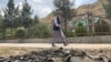 FILE - A man walks past the site of a suicide attack along the roadside in Faizabad district of Badakhshan province on June 6, 2023.