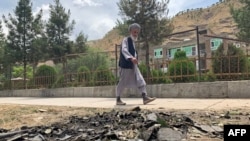 FILE - A man walks past the site of a suicide attack along the roadside in Faizabad district of Badakhshan province on June 6, 2023.