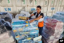 FILE - United Nations and Red Crescent workers prepare aid for distribution to Palestinians at UNRWA warehouse in Deir Al-Balah, Gaza Strip, Oct. 23, 2023.