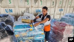 FILE - U.N. and Red Crescent workers prepare aid for distribution to Palestinians at UNRWA warehouse in Deir Al-Balah, Gaza Strip, Oct. 23, 2023.
