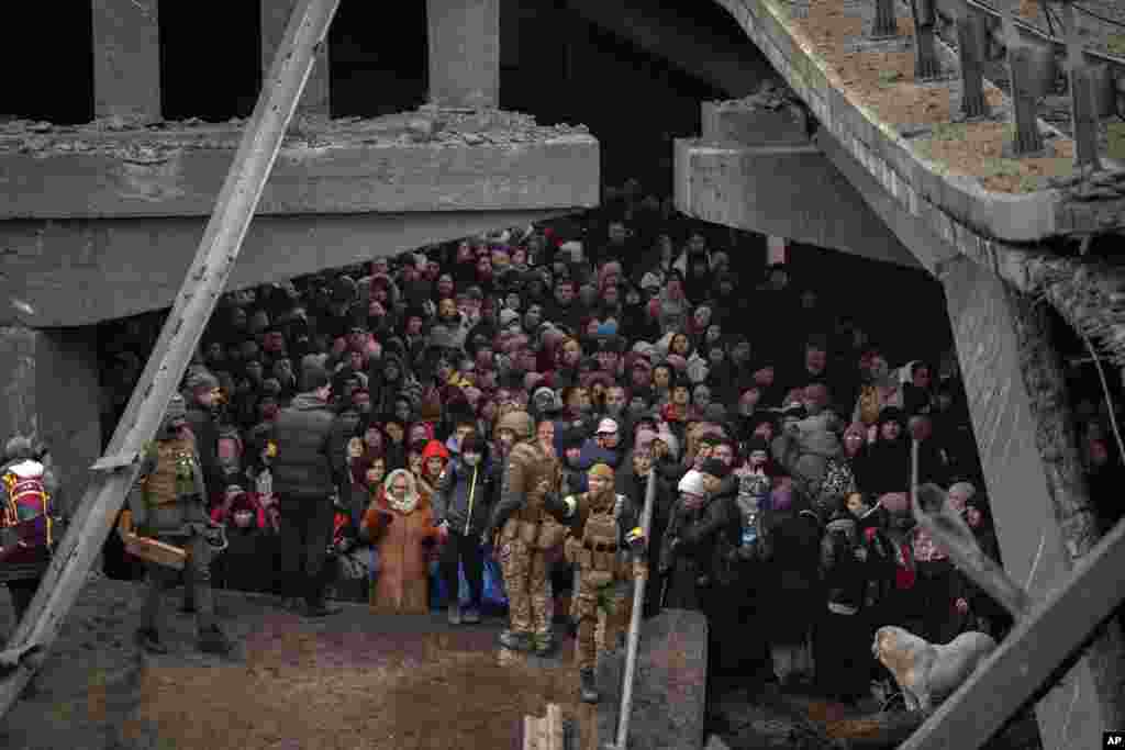 Люди под разрушенным мостом в ожидании эвакуации через реку Ирпень, 5 марта 2022. (AP Photo/Emilio Morenatti)