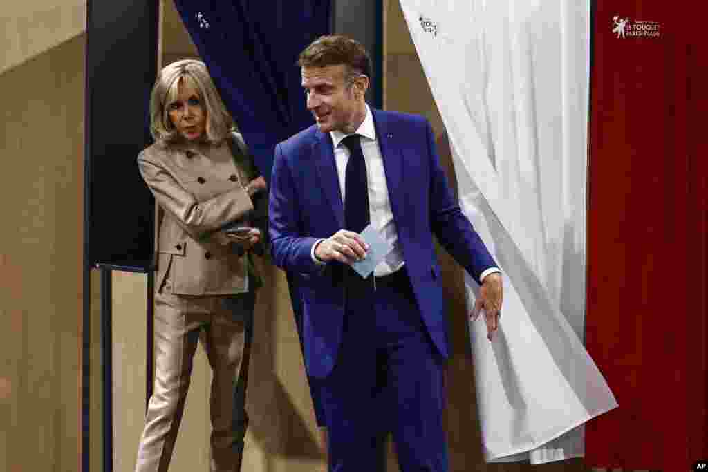 French President Emmanuel Macron and his wife Brigitte Macron leave the voting booth in Le Touquet-Paris-Plage, northern France.