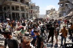 Palestinians carry some salvaged belongings as they leave the Jabalia refugee camp in the northern Gaza Strip after they returned briefly to check on their homes on May 30, 2024.