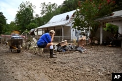 FILE - Teresa Reynolds sits as members of her community clean the debris from their flood ravaged home at Ogden Hollar in Hindman, Ky., July 30, 2022. (AP Photo/Timothy D. Easley, File)