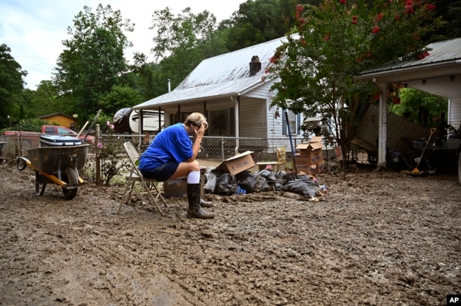 FILE - Teresa Reynolds sits as members of her community clean the debris from their flood ravaged home at Ogden Hollar in Hindman, Ky., July 30, 2022. (AP Photo/Timothy D. Easley, File)