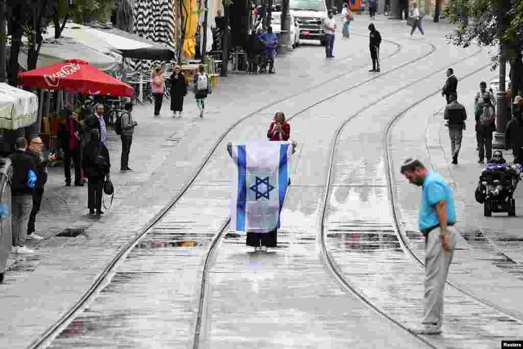 Orang-orang menghentikan kegiatan saat sirene berdurasi dua menit memperingati Hari Peringatan Holocaust Israel, di Yerusalem, Senin, 6 Mei 2024. (Foto: Nir Elias/Reuters)