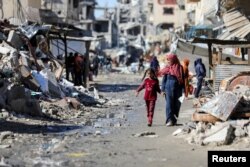 Palestinci hodaju pored ruševina stambenih zgrada uništenih u izraelskoj ofanzivi, u gradu Gaza, 20. marta 2024.
