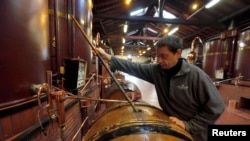 资料照：一名技术专家在法国西南部的拿破仑干邑酒厂检查蒸馏工序。（2015年2月11日）
