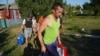 FILE - Villagers carry their belongings as they evacuate from their home village of Monachynivka close to the site of heavy battles against the Russian troops in the Kharkiv region, July 16, 2024. 