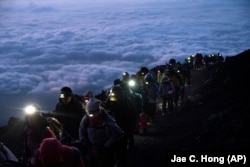 FILE -A group of hikers climb to the top of Mount Fuji just before sunrise as clouds hang below the summit Tuesday, Aug. 27, 2019, in Japan. (AP Photo/Jae C. Hong, File)