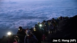 资料照：一群游客凌晨攀登日本富士山观看日出美景。（2019年8月27日）