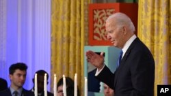 President Joe Biden waves to people attending a Hanukkah reception in the East Room of the White House in Washington on Monday, December 11, 2023.