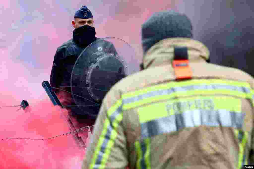 A police officer guards the area as firefighters attend a protest in Brussels, Belgium.