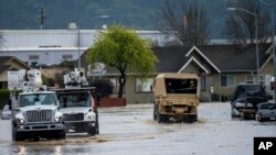 Utility vehicles and emergency personnel drove through floodwaters in Watsonville, Calif., March 11, 2023. 