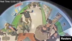 Law enforcement officers stage in a hallway after Salvador Ramos entered Robb Elementary school to kill 19 children and two teachers in Uvalde, Texas, U.S. May 24, 2022 in a still image from surveillance video. 
