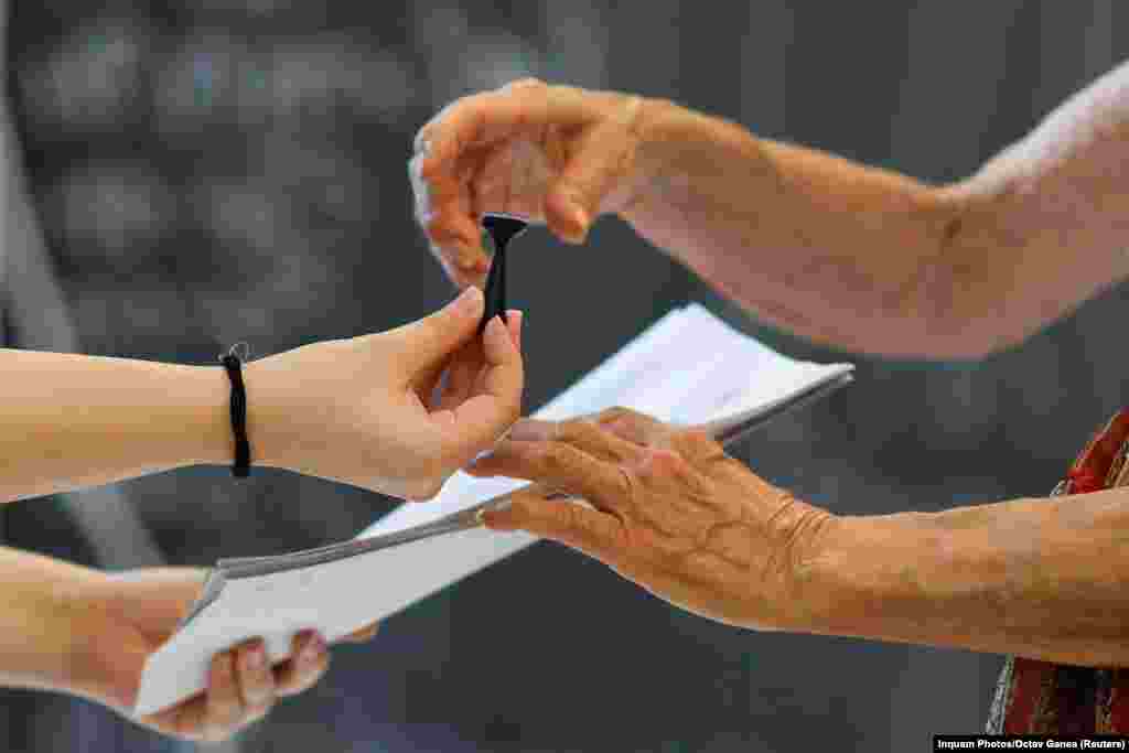A woman receives a stamp and voting ballots to cast her vote for the European Parliament election and the local elections, in Bucharest, Romania, June 9, 2024. 