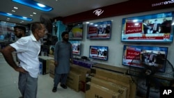 Warga menyaksikan televisi di sebuah toko elektronik, di Karachi, Pakistan, yang menyiarkan berita tentang mantan Perdana Menteri Pakistan Imran Khan Kamis, 11 Mei 2023. (AP/Fareed Kha8)