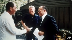 FILE - Egypt's President Anwar Sadat, left, shakes hands with Israeli Prime Minister Menachem Begin as U.S. President Jimmy Carter looks on at Camp David, Md., Sept. 7, 1978. The presidential retreat has been the site of decades of diplomatic meetings.