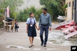 Gautam Dongre, right, of the National Alliance of Sickle Cell Organizations, and his daughter Sumedha, a patient of sickle cell disease walk through their neighborhood in Nagpur, India, Wednesday, Dec. 6, 2023. (AP Photo/Ajit Solanki)