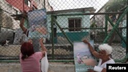 Warga memasang sejumlah poster yang berisi pengumuman tentang pemilu legislatif di Havana, Kuba, pada 25 Maret 2023. (Foto: Reuters/Alexandre Meneghini)