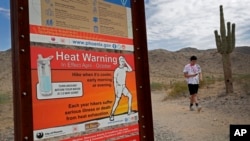 FILE - A hiker finishes his morning walk at the South Mountain Preserve to beat the high temperatures, in Phoenix, July 11, 2019.