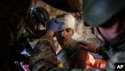 Ukrainian soldiers and police officer provide first aid to a man injured by Russian shelling at the residential neighborhood near Kostiantynivka, Ukraine, March 10, 2023. 