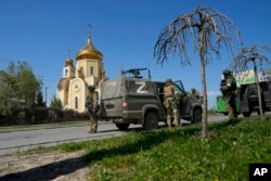 FILE - Russian servicemen guard an area in front of an Orthodox church in Berdyansk, eastern Ukraine, April 30, 2022. (AP Photo)
