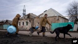 Hennadiy Mazepa and his wife, Natalia Ishkova, walk along the road as they collect wood from houses destroyed by Russian shelling in Chasiv Yar, Ukraine, March 3, 2023.