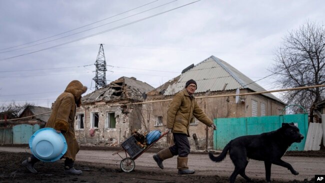 Hennadiy Mazepa y su esposa, Natalia Ishkova, caminan mientras recolectan madera de casas destruidas por bombardeos rusos en Chasiv Yar, Ucrania, 3 de marzo de 2023