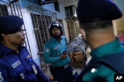 Petugas keamanan berdiri di dekat mayat orang yang tewas dalam kebakaran kereta api di Dhaka, Bangladesh, Selasa, 19 Desember 2023. (AP/Mahmud Hossain Opu)