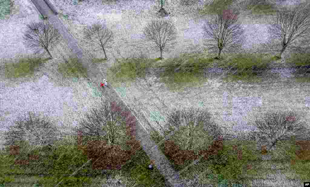 People walk though a park as snow falls in Frankfurt, Germany.