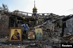 A woman collects Orthodox icons at a site of a church destroyed by a Russian missile strike, amid Russia's attack on Ukraine, in the village of Komyshuvakha, Zaporizhzhia region, Ukraine, Apr. 16, 2023.