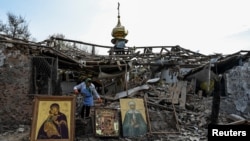 A woman collects Orthodox icons at a site of a church destroyed by a Russian missile strike, amid Russia's attack on Ukraine, in the village of Komyshuvakha, Zaporizhzhia region, Ukraine, Apr. 16, 2023.