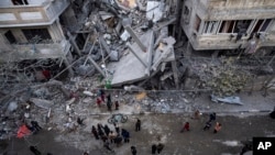 Warga Palestina memeriksa kerusakan pada sebuah gedung yang hancur akibat serangan Israel di Rafah, di selatan Jalur Gaza, pada 24 Maret 2024. (Foto: AP/Fatima Shbair)
