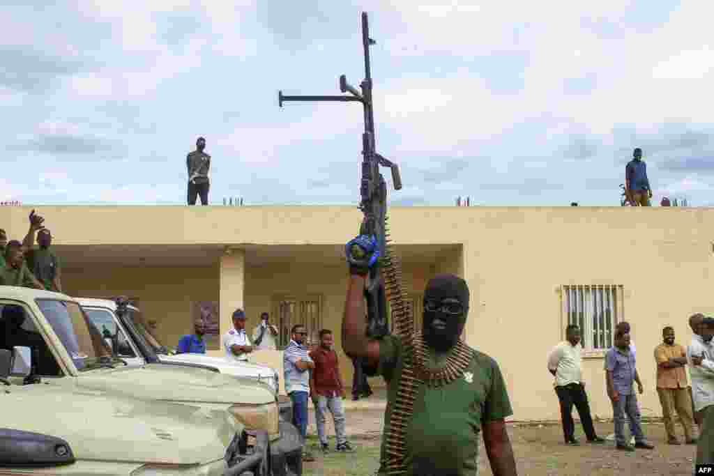 Members of a 'joint security cell' made up of various military and security services affiliated with Sudan's army, brandish rifles as they take part in a parade in Gedaref city in the east of the war-torn country, July 28, 2024. 