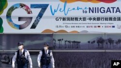 日本警察巡邏走過新瀉街頭張貼的七國集團財長會議宣傳畫。（2023年5月10日）