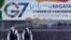 日本警察巡逻走过新泻街头张贴的七国集团财长会议宣传画。（2023年5月10日）