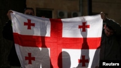 Activists hold a Georgian flag at a rally outside a parliament building during a plenary session of parliament on the controversial "foreign agents" bill, that sparked mass protests in recent days, in Tbilisi, Georgia, March 10, 2023.