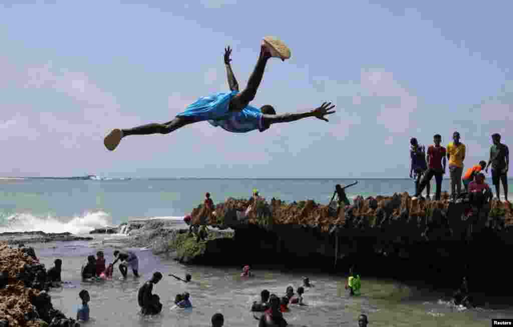 A man jumps into the waters of the Indian Ocean to join other revelers in Hamarweyne district of Mogadishu, Somalia