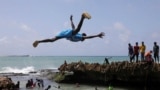 A man jumps into the waters of the Indian Ocean to join other revelers in Hamarweyne district of Mogadishu, Somalia