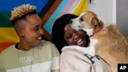 Ella Anthony, left, and her partner Doris Ezuruike Chinons pose for a photo with their dog Paddy, during an interview in their house in Passo Corese, near Rome, Italy, March 11, 2024.