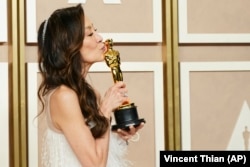 Michelle Yeoh mencium Piala Oscar yang berhasil diraihnya. (Jordan Strauss/AP)