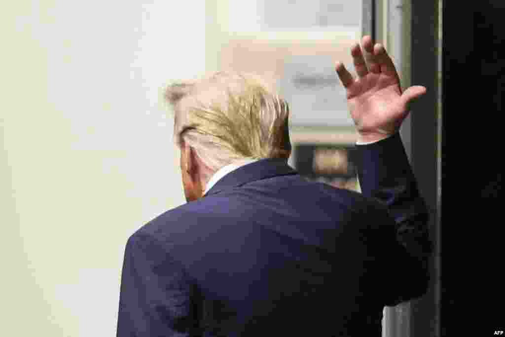 Former U.S. President Donald Trump gestures while walking in a hallway outside the courtroom as he attends his trial for allegedly covering up hush money payments linked to extramarital affairs, at Manhattan Criminal Court in New York City.