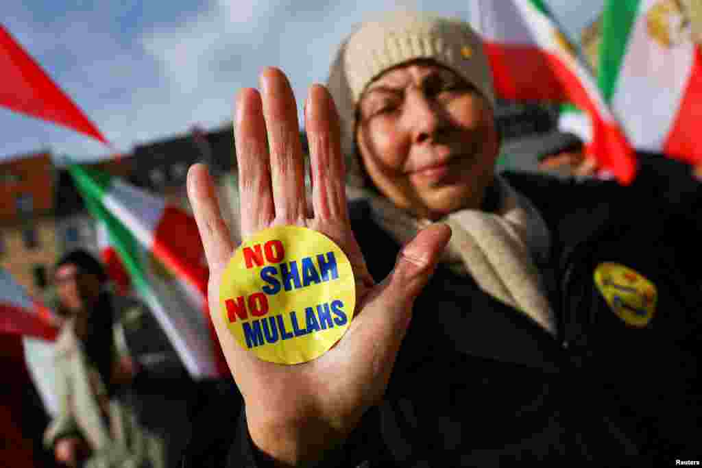 A person shows a sticker as people hold Iranian flags during a protest on the day of the Munich Security Conference in Germany.