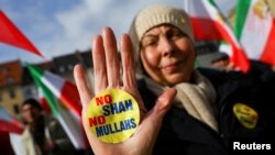 A person shows a sticker as people hold Iranian flags during a protest on the day of the Munich Security Conference in Germany.