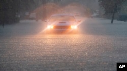 A driver blinks their hazard lights as heavy rain falls over parts of South Florida on June 12, 2024, in Hollywood, Fla.